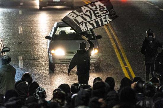 2020年11月3日，美国西雅图，一名抗议者在反种族主义抗议活动中挥舞着一面写着“黑命攸关”的旗帜。
